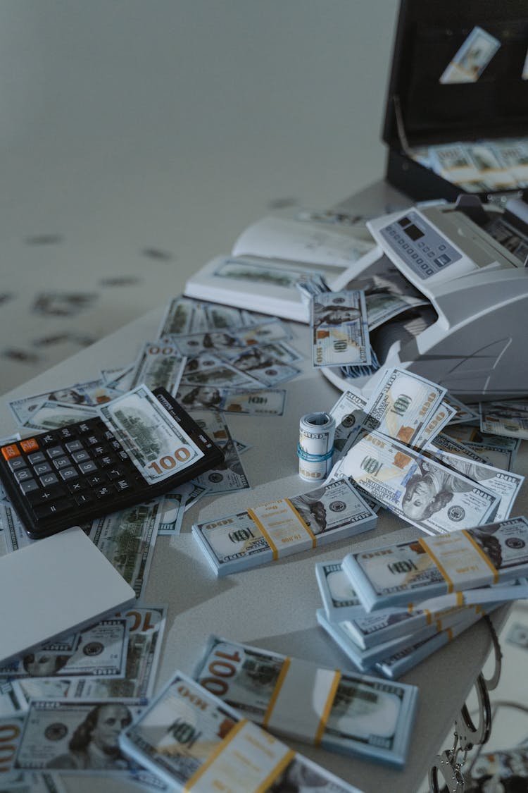 Money Counter Machine And Bundles Of Cash Of A White Surface