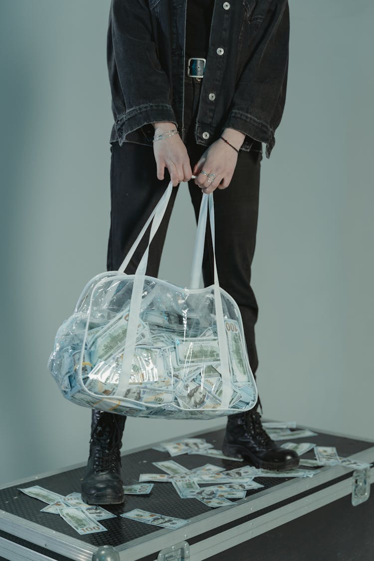 Person In Black Jacket Holding Big Transparent Bag With Money