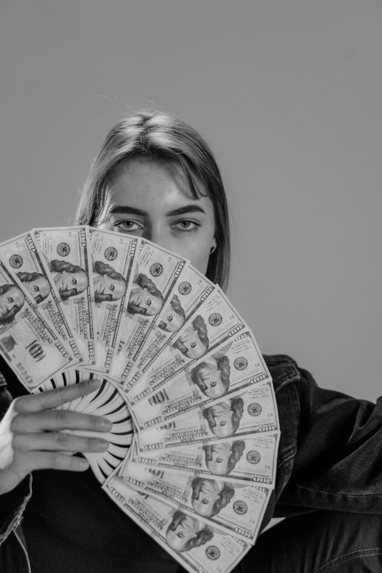 Woman Covering Face With Hand Fan Made Of Paper Money