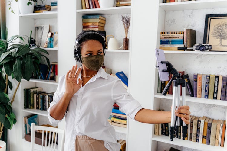 Woman With Mask Waving Hand In Front Of Smartphone