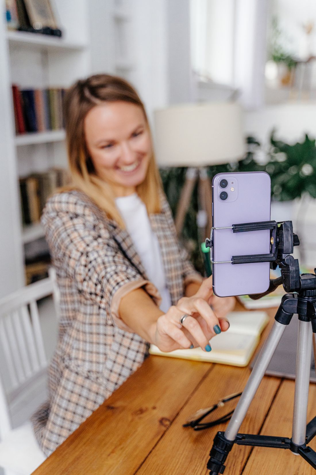 Shop owner setting up a phone on a tripod to film in her home studio — Adventure Studio on Pexels