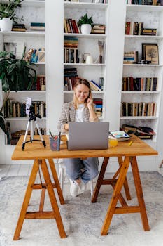 Woman using a laptop for online teaching in a cozy home office setting.