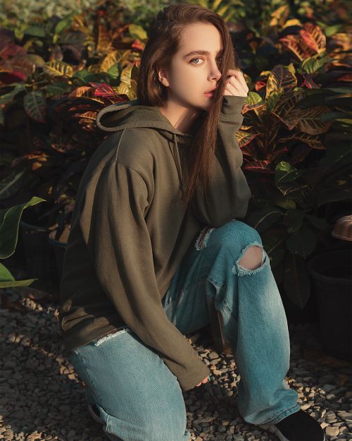 Free Young woman with ripped jeans posing stylishly in a lush garden. Stock Photo