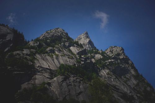 Free From below of massive rocky mountain with sharp peaks against blue sky in evening Stock Photo