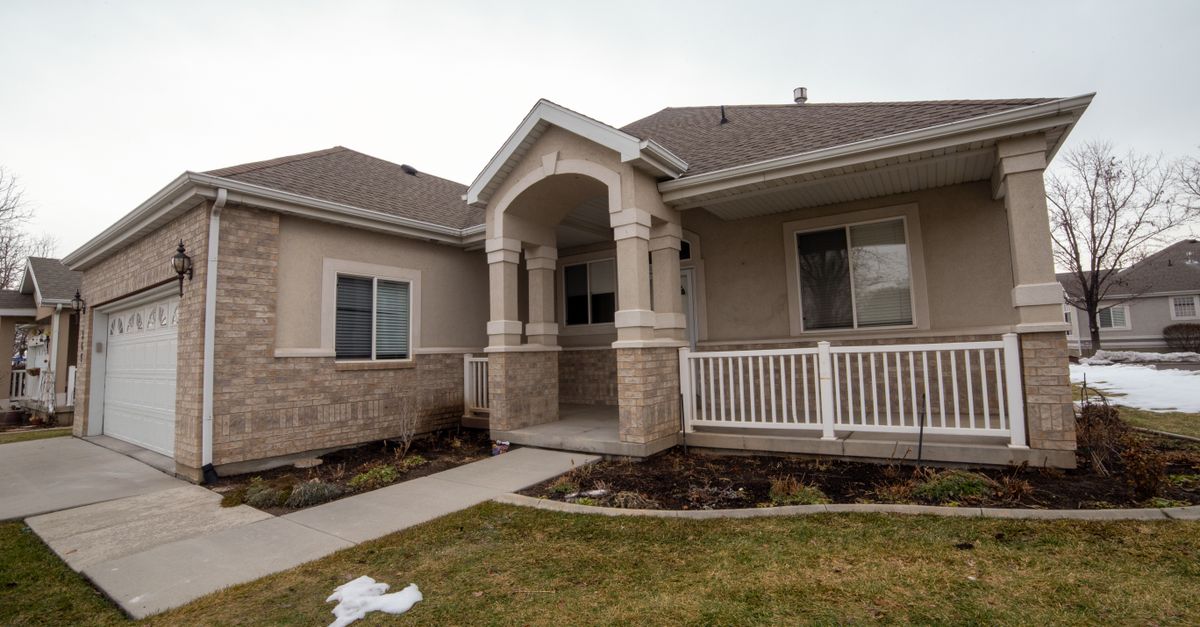 A modern suburban home captured in winter, featuring a spacious porch and a snowy yard.
