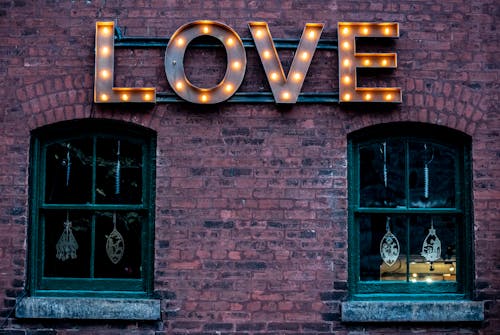 Free Light Letters Near Windows on Brick Wall Stock Photo