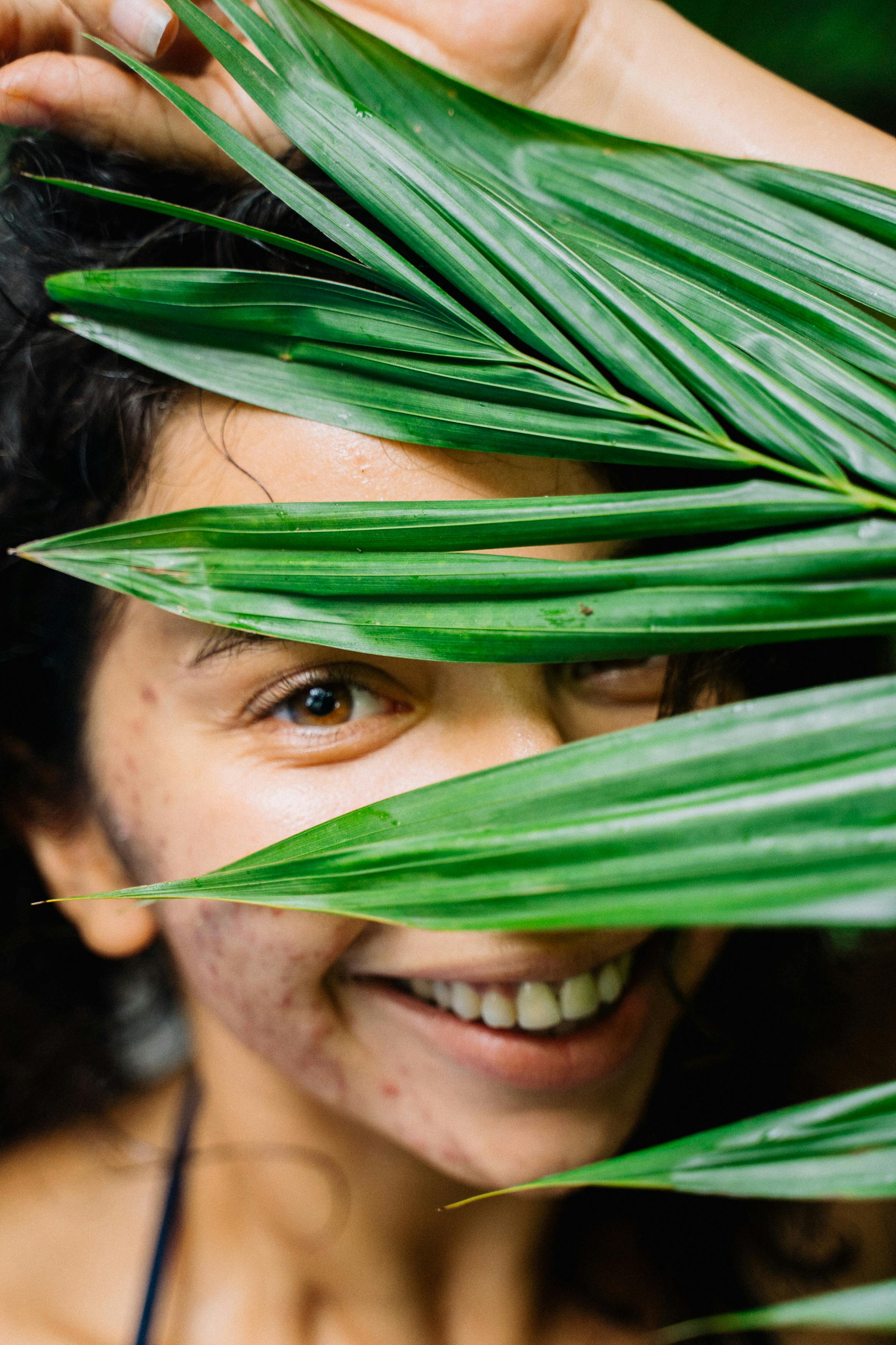 Free Smiling Woman Behind Green Leaves Stock Photo