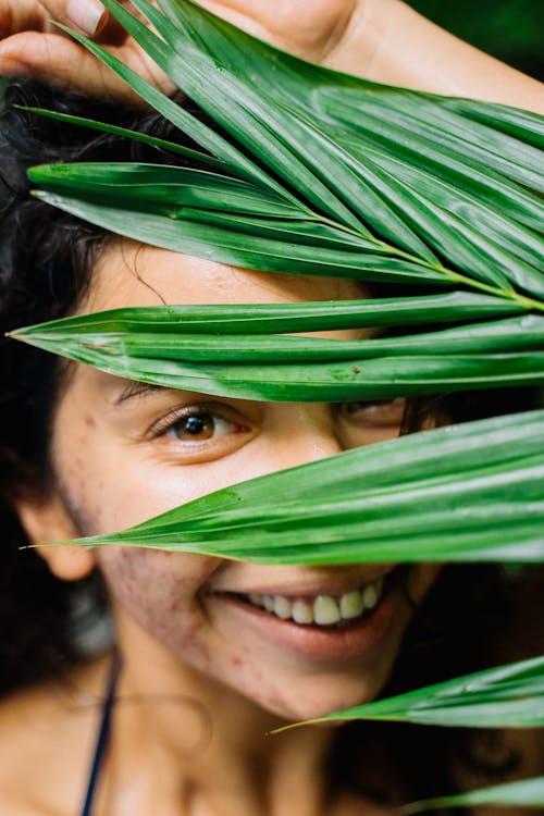 Free Smiling Woman Behind Green Leaves Stock Photo