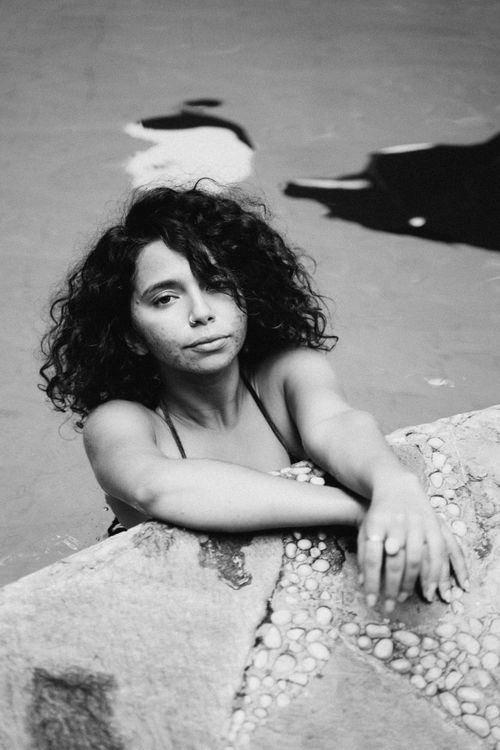 Free Black and white portrait of a woman with curly hair in a swimming pool. Stock Photo