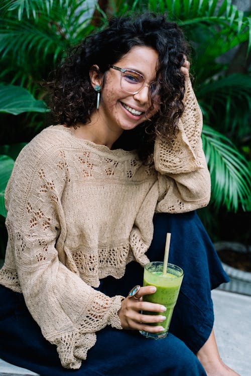 Woman in Beige Knitted Sweater Holding a Green Smoothie