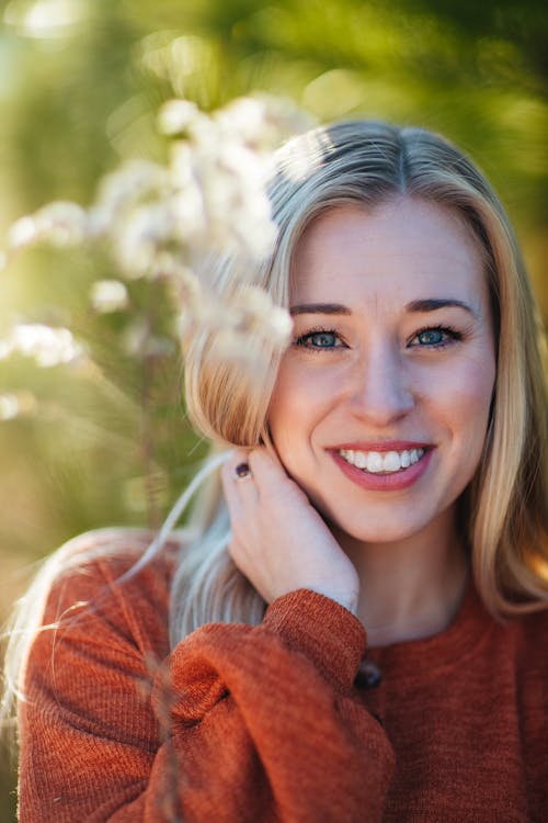 Beautiful young woman standing on sunny abundant nature background