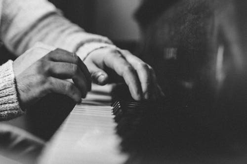 A Grayscale of a Person Playing the Piano