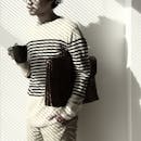 一名穿着条纹衬衫的成年男子，在极简主义的环境中拿着咖啡和包