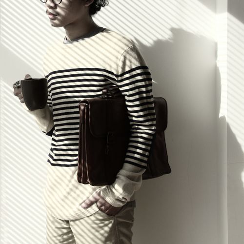 Free Adult man holding coffee and bag, wearing striped shirt, in a minimalist setting. Stock Photo