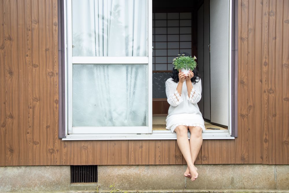 鉢植えのそばに腰掛ける人