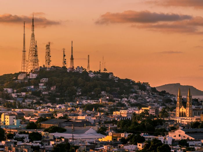 A breathtaking view of Mazatlán's skyline and cathedral at sunset with vibrant orange hues.