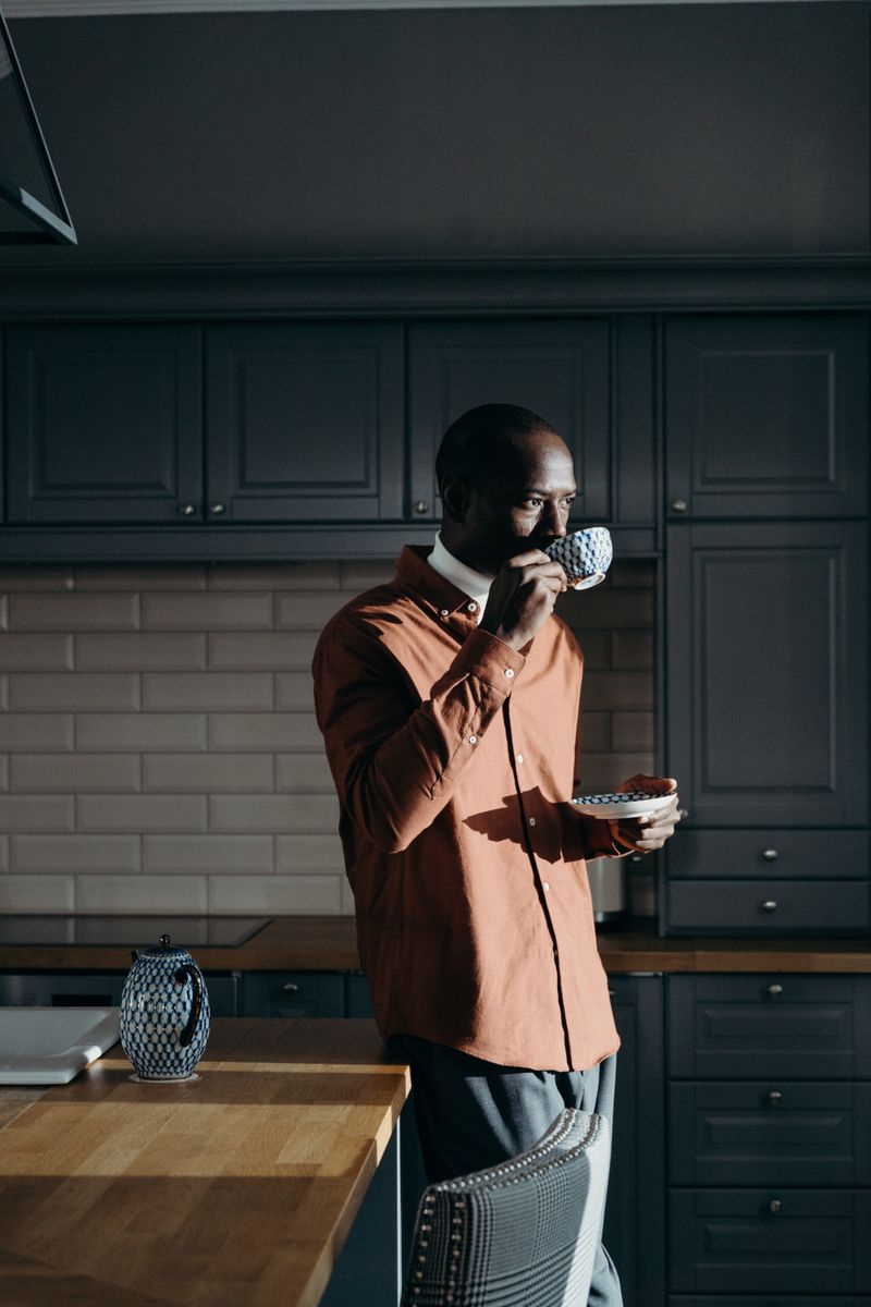 Black African man drinking herbal tea in kitchen – natural constipation relief Nigeria