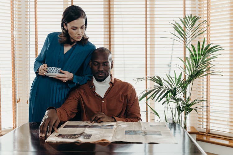 A Man And A Woman Reading A Newspaper