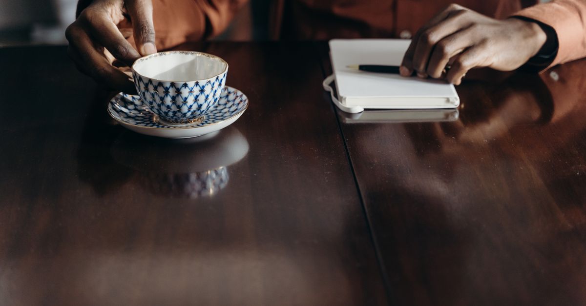 hand writing in a journal with a cup of tea and soft lighting