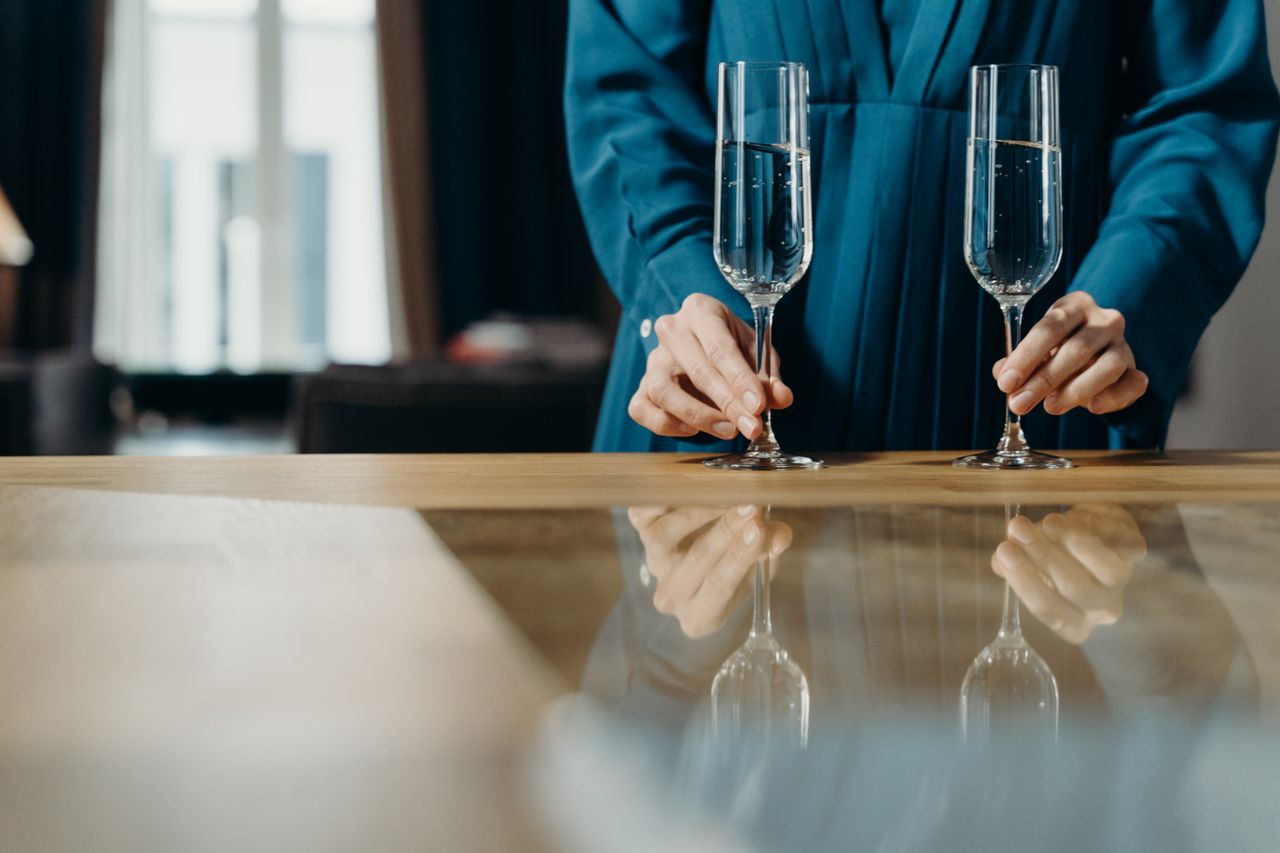 person in blue attire elegantly setting champagne glasses on a table i