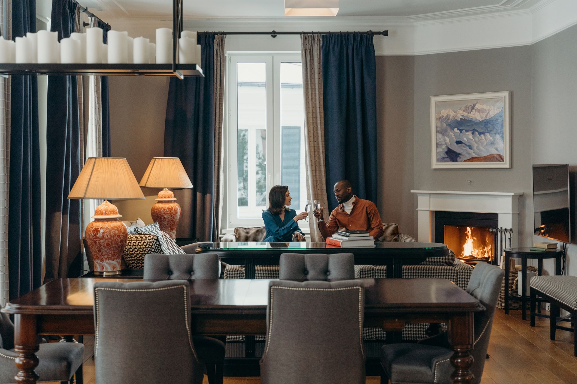 Couple enjoying wine in a cozy living room by the fireplace with a warm ambiance.