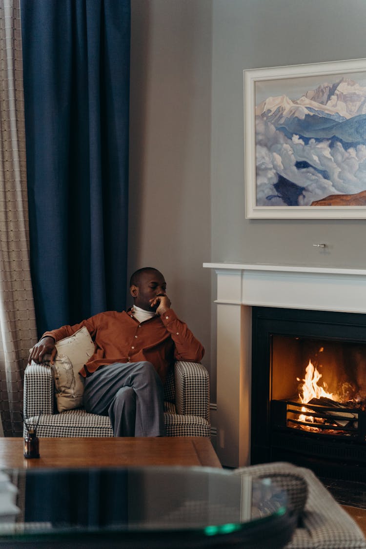 Man Sitting On Sofa Chair Near Fireplace