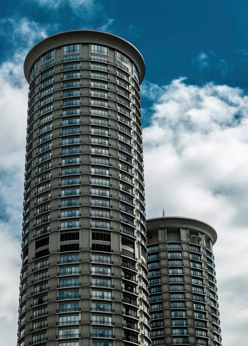 Free Vertical shot of modern cylindrical skyscrapers against a blue sky in Seattle, WA. Stock Photo
