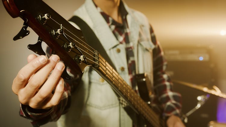 A Person Tuning A Bass Guitar