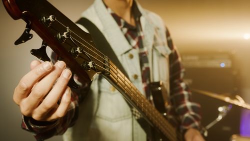 Free Detail shot of a musician tuning a bass guitar in a studio with warm lighting. Stock Photo
