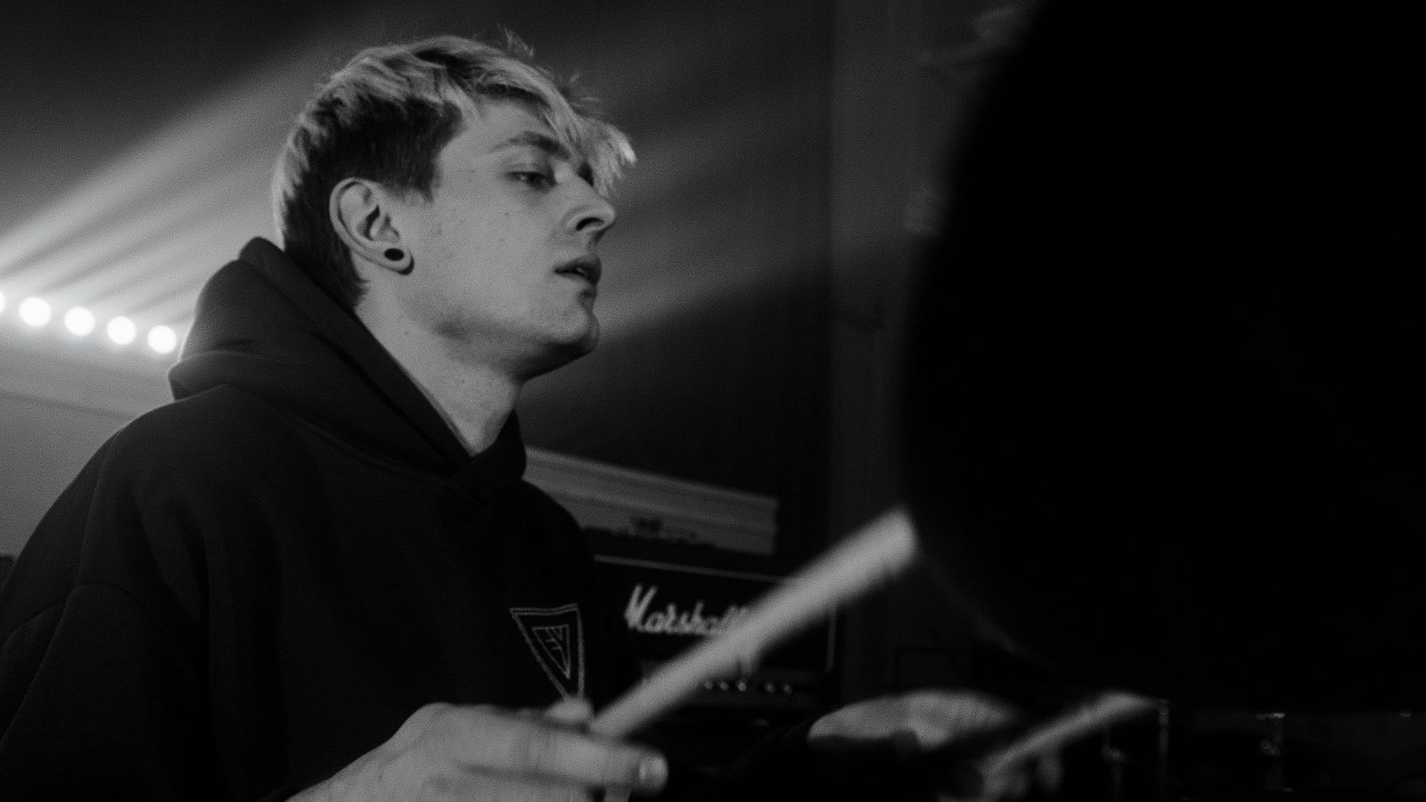 Black and white image of a drummer playing with full intensity — the effort required to push past comfortable territory
