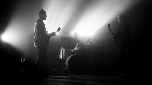 Free A monochrome image of a band performing live with dramatic lighting effects. Stock Photo