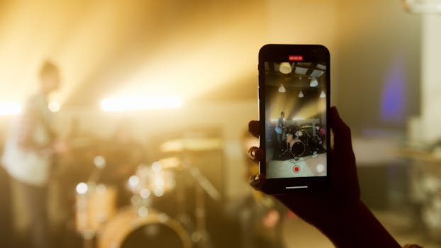 A smartphone captures a live band performance in a warm, atmospheric setting.