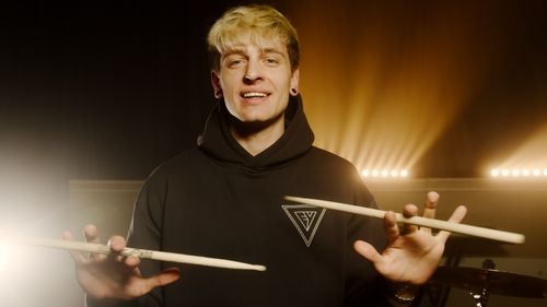 Free Energetic drummer displaying his skills with drumsticks in a well-lit music studio. Stock Photo