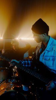Energetic band performance featuring a guitarist and drummer under vibrant stage lighting.