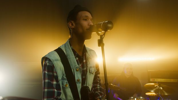 A vibrant scene of a young musician passionately singing into a microphone under stage lights.