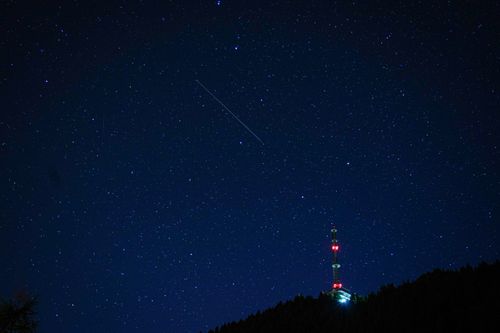 Free A mesmerizing view of a starry night sky with a broadcasting tower silhouette on the horizon. Stock Photo