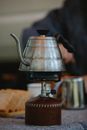 Hot steel gooseneck coffee kettle placed on burning portable gas stove on table