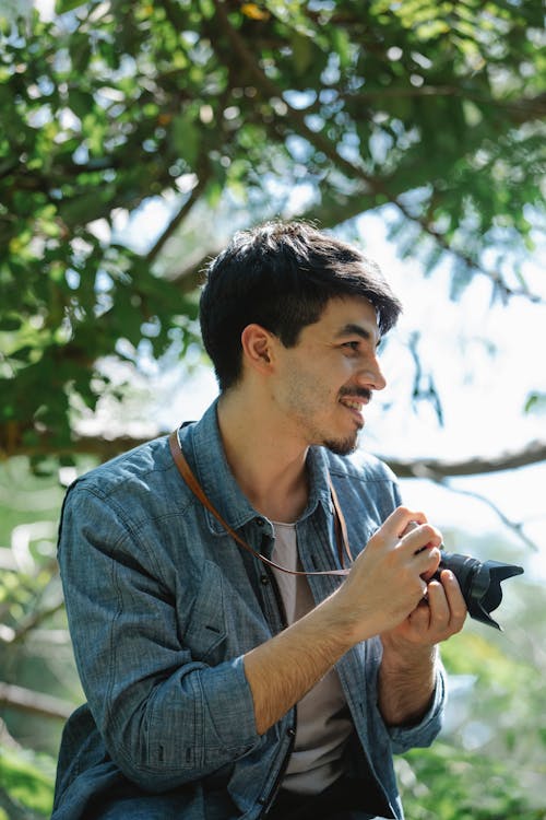 Smiling man with photo camera in sunny garden