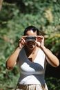 Cheerful woman looking in binoculars in sunny forest