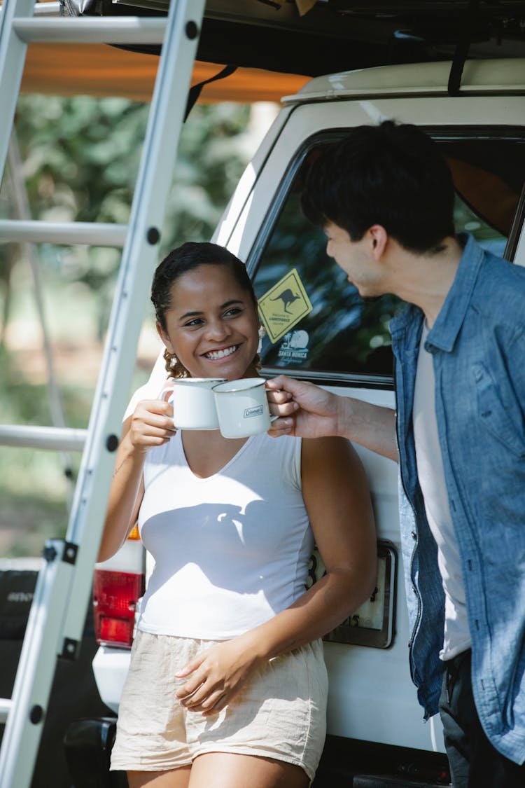 Smiling Diverse Couple Clinking Cups Of Coffee In Countryside