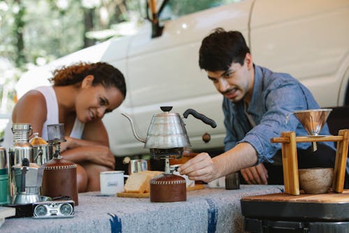 Diverse couple switching portable stove to boil water during picnic