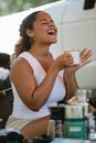 Laughing ethnic woman enjoying hot coffee in campsite