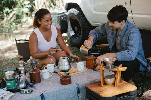 Couple enjoying a fresh coffee brewing experience during a camping picnic outdoors.