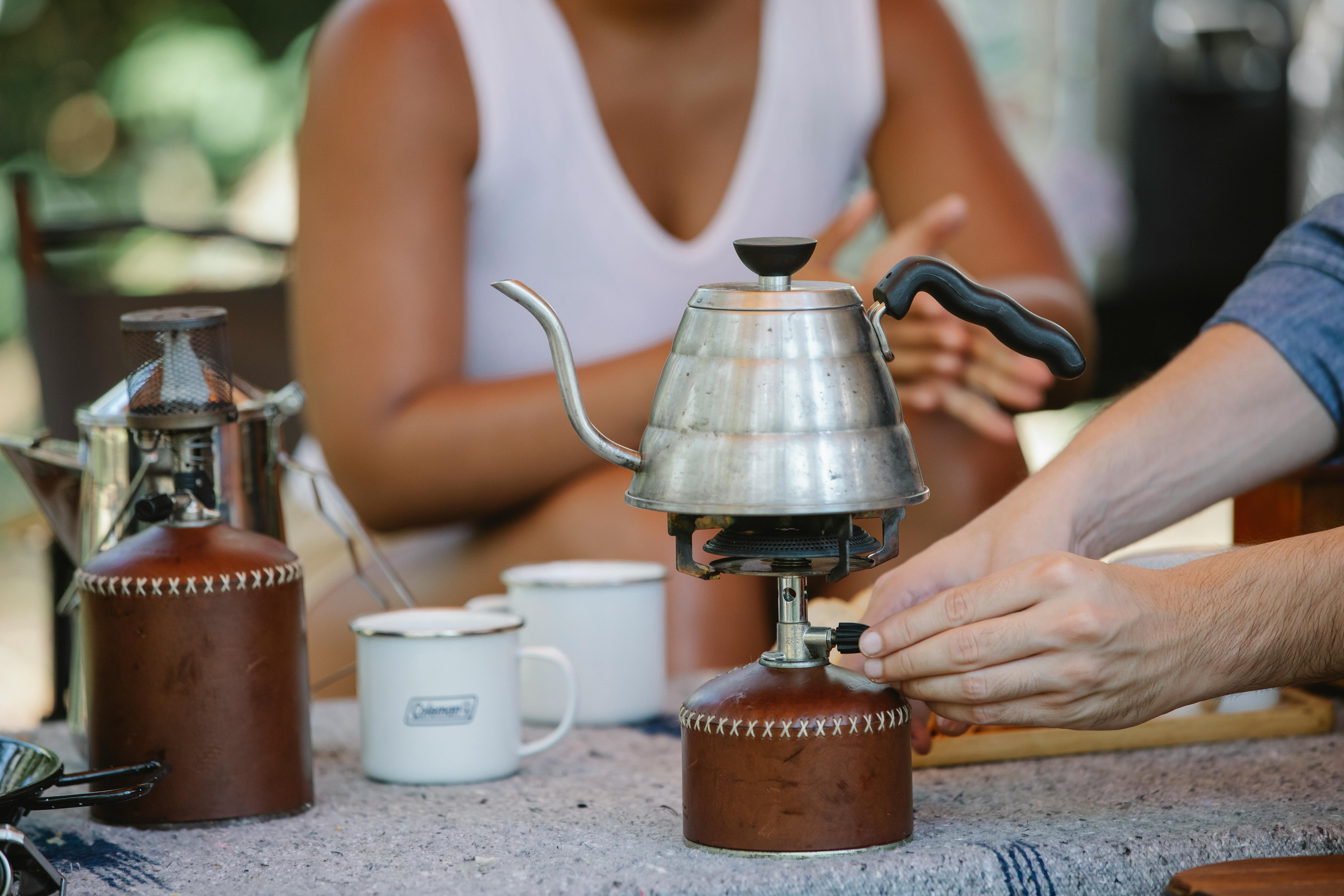 crop couple heating metal kettle on camp stove