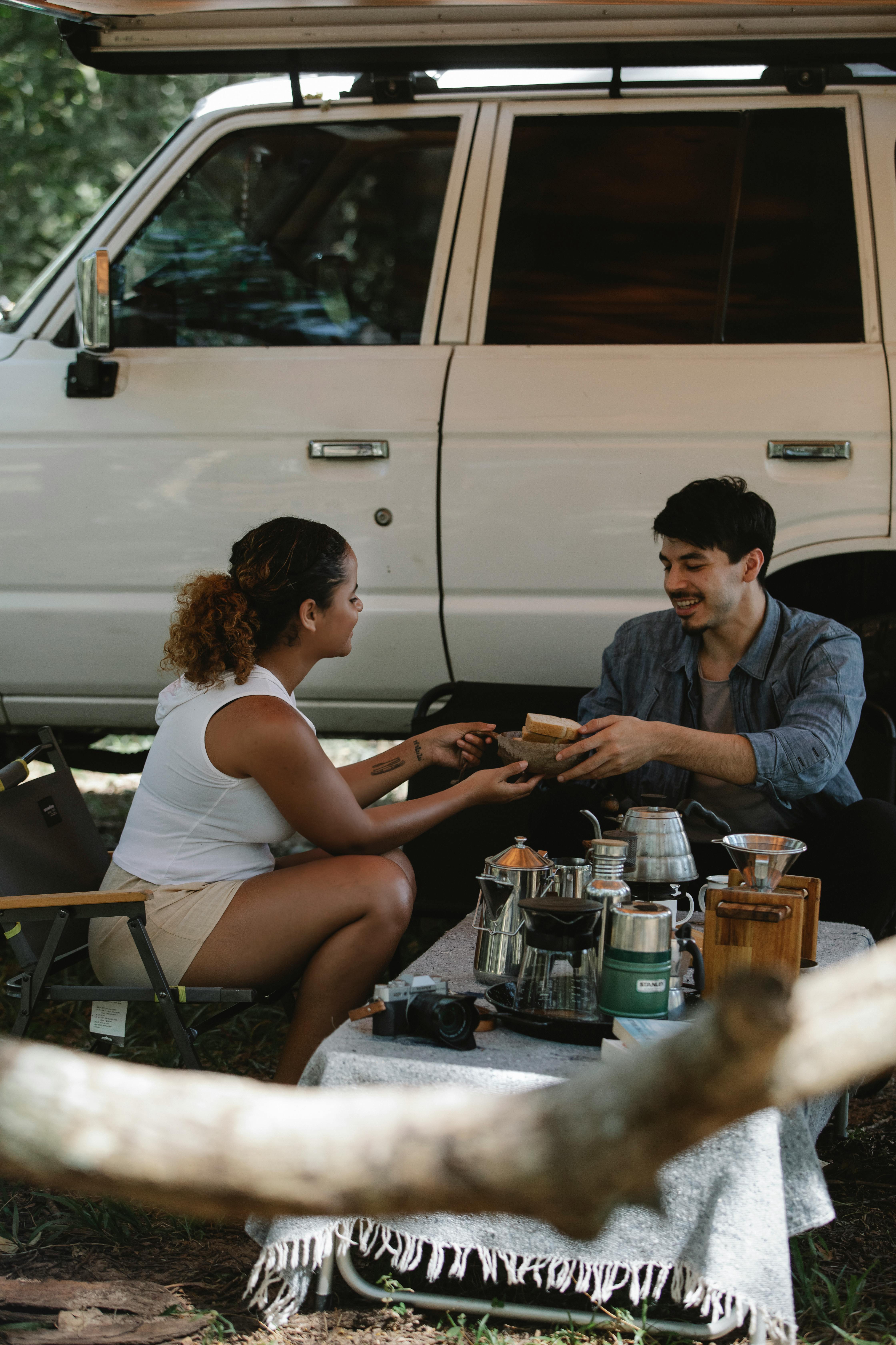 positive young diverse couple having lunch during holiday in forest