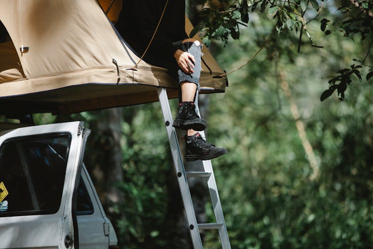 Unrecognizable Traveler Resting In Camping Tent Placed On Off Road Car