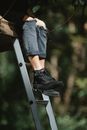 Person sitting on high ladder in park
