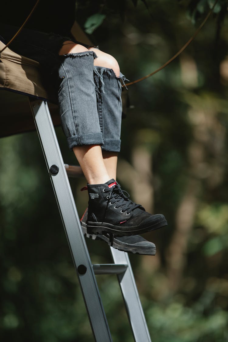 Person Sitting On High Ladder In Park