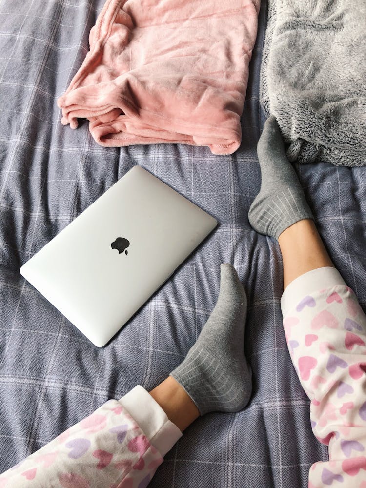 Feet With Socks On Bed Near Laptop