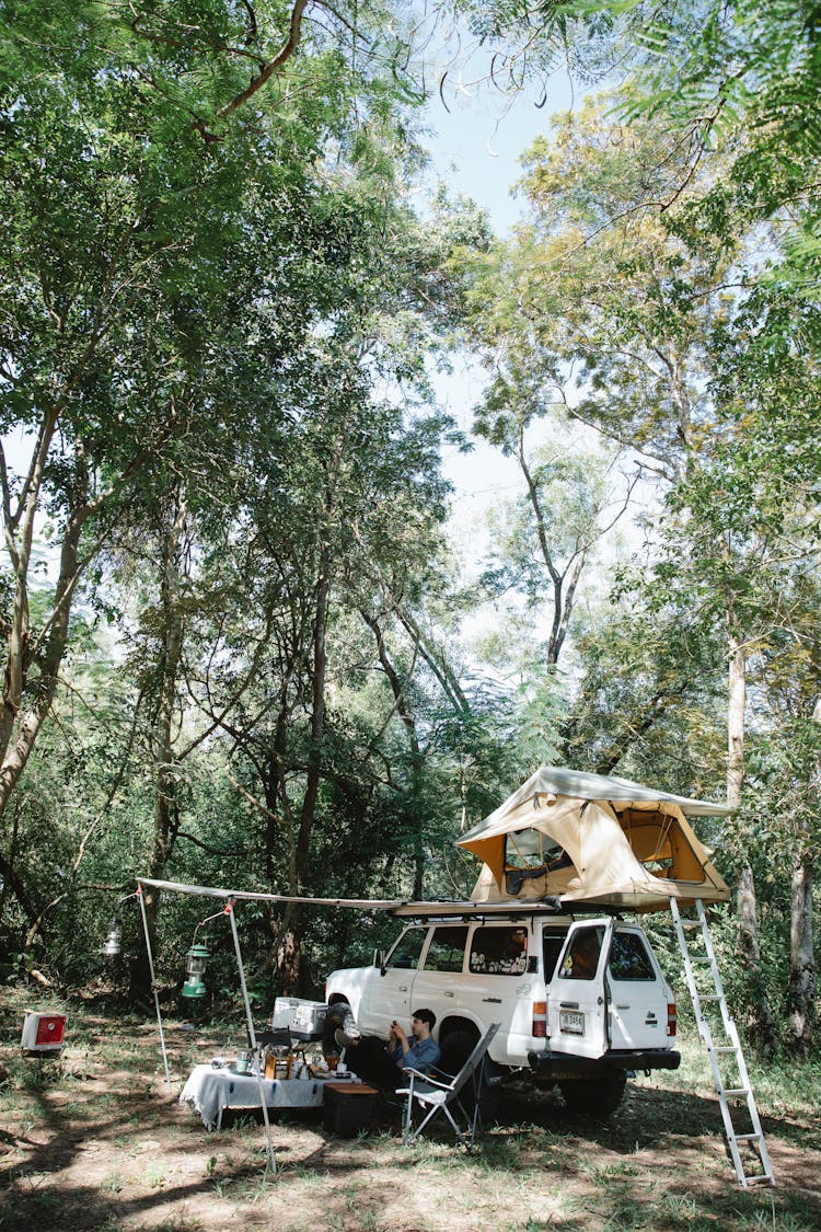 Camping Car With Tent On Roof Parked In Forest In Sunlight